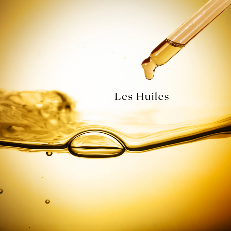 Affiche sur fond doré montrant une pipette déposant une goutte d’huile, avec la mention « Les Huiles ». L’image évoque des huiles pour le visage, mettant en avant douceur et soin naturel.